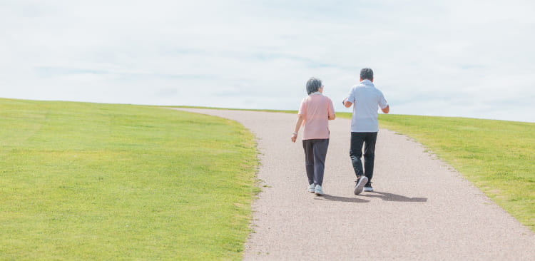 広い芝生の中を歩いている二人の人物の後ろ姿