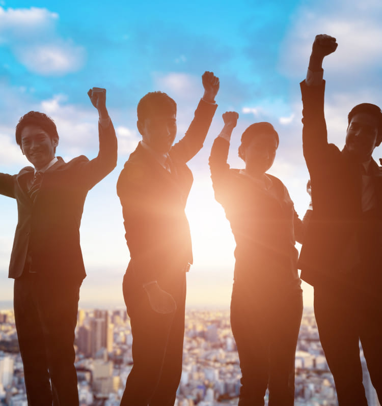 都市の背景を背に、ビジネススーツを着た複数の人々が拳を突き上げているシルエット